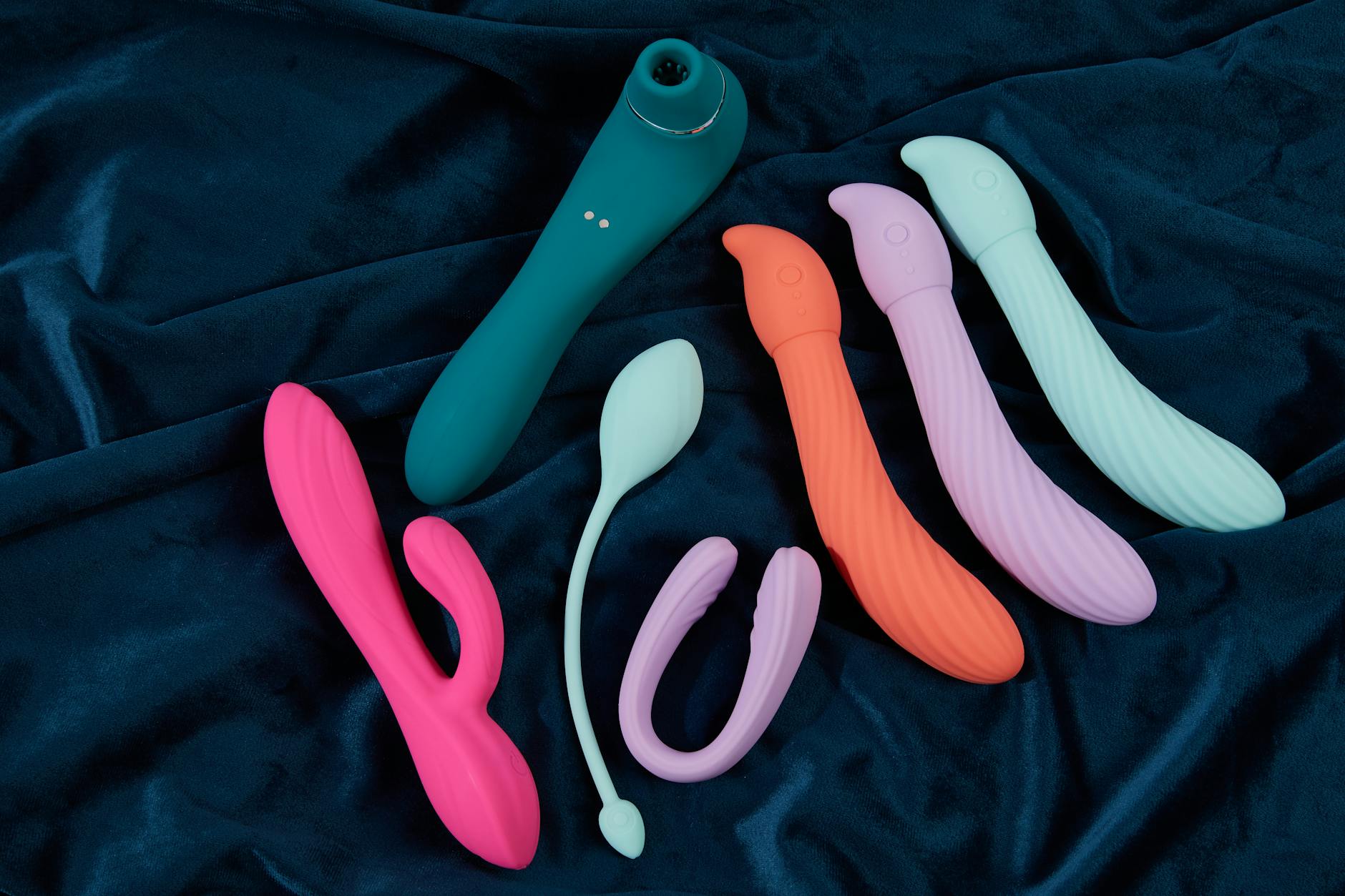 Mano che tiene un vibratore arancione su sfondo viola minimalista, che mostra sensualità moderna