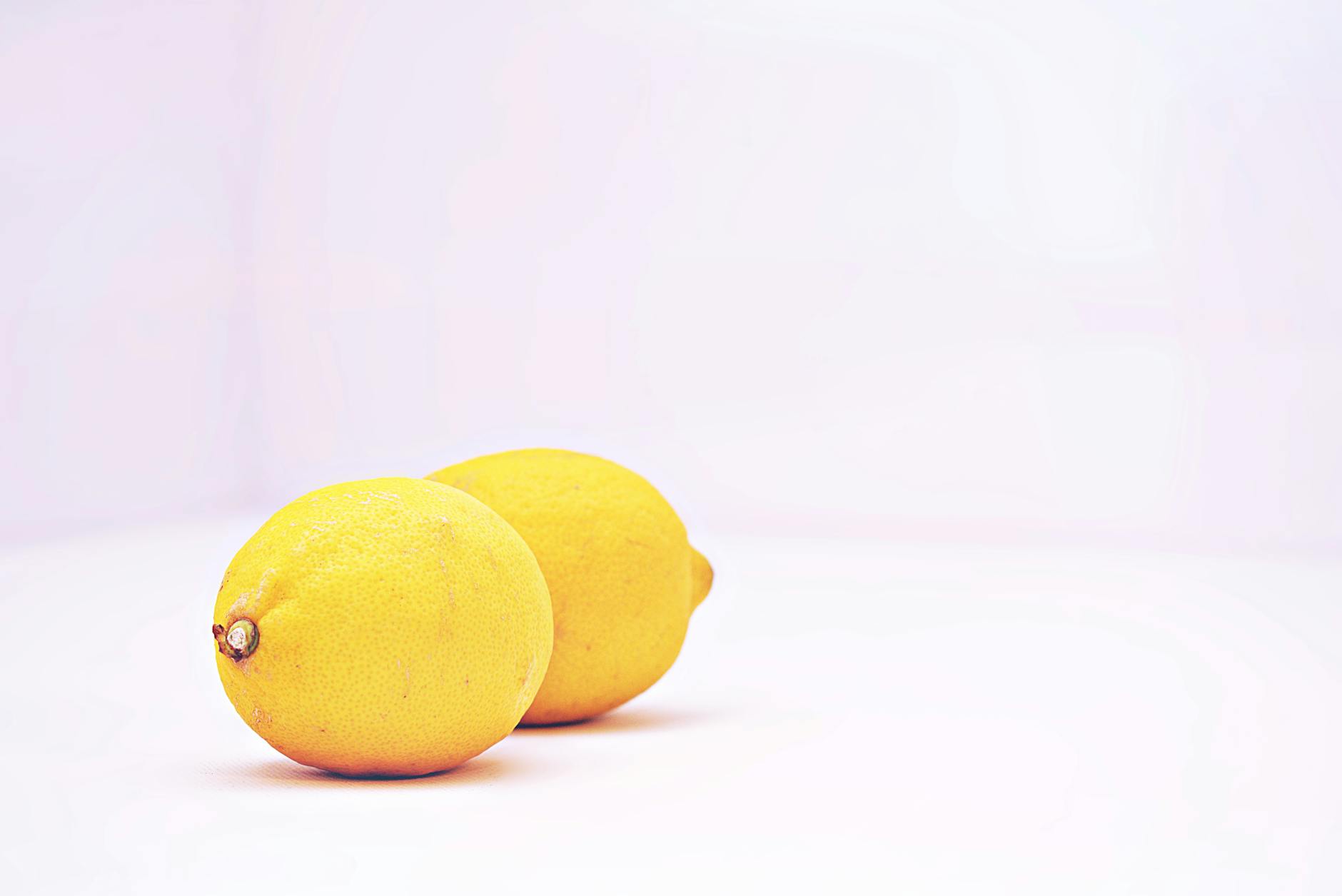 Due limoni vibranti su sfondo bianco minimalista, che simboleggiano freschezza e rinascita della sensibilità