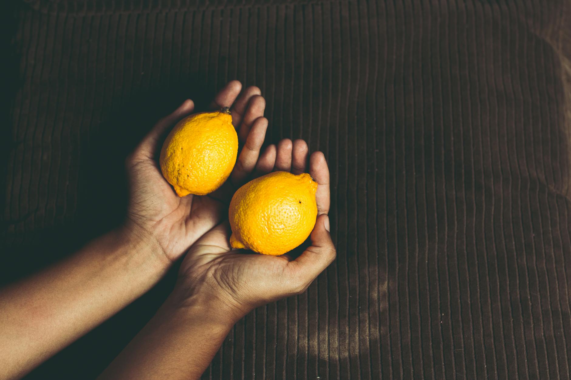 Due limoni freschi tenuti in mano, simbolo di freschezza e vitalità sensoriale