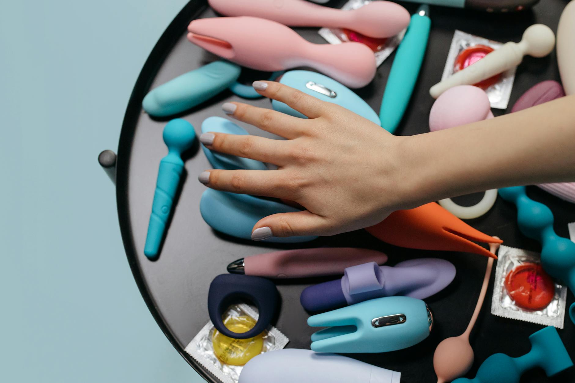 Mani che tengono un vibratore blu delicato contro un maglione in maglia
