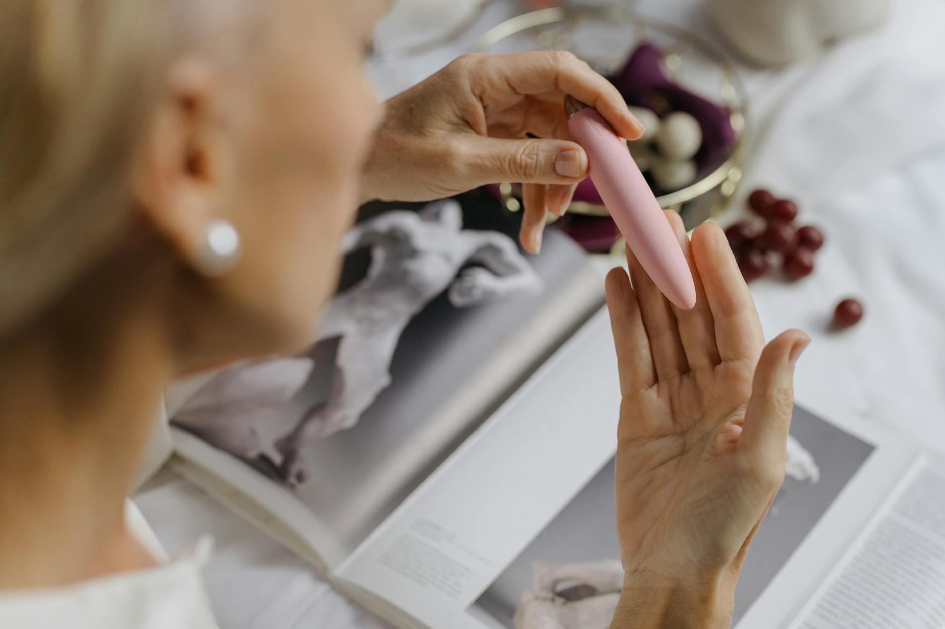 Donna con occhiali che tiene fermi due vibratori in silicone blu e rosa, con espressione contemplativa