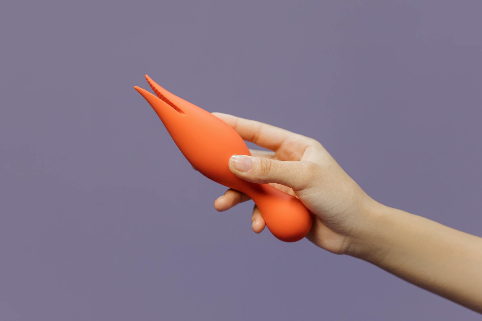 Mano che tiene un vibratore al limone moderno su uno sfondo minimalista viola.