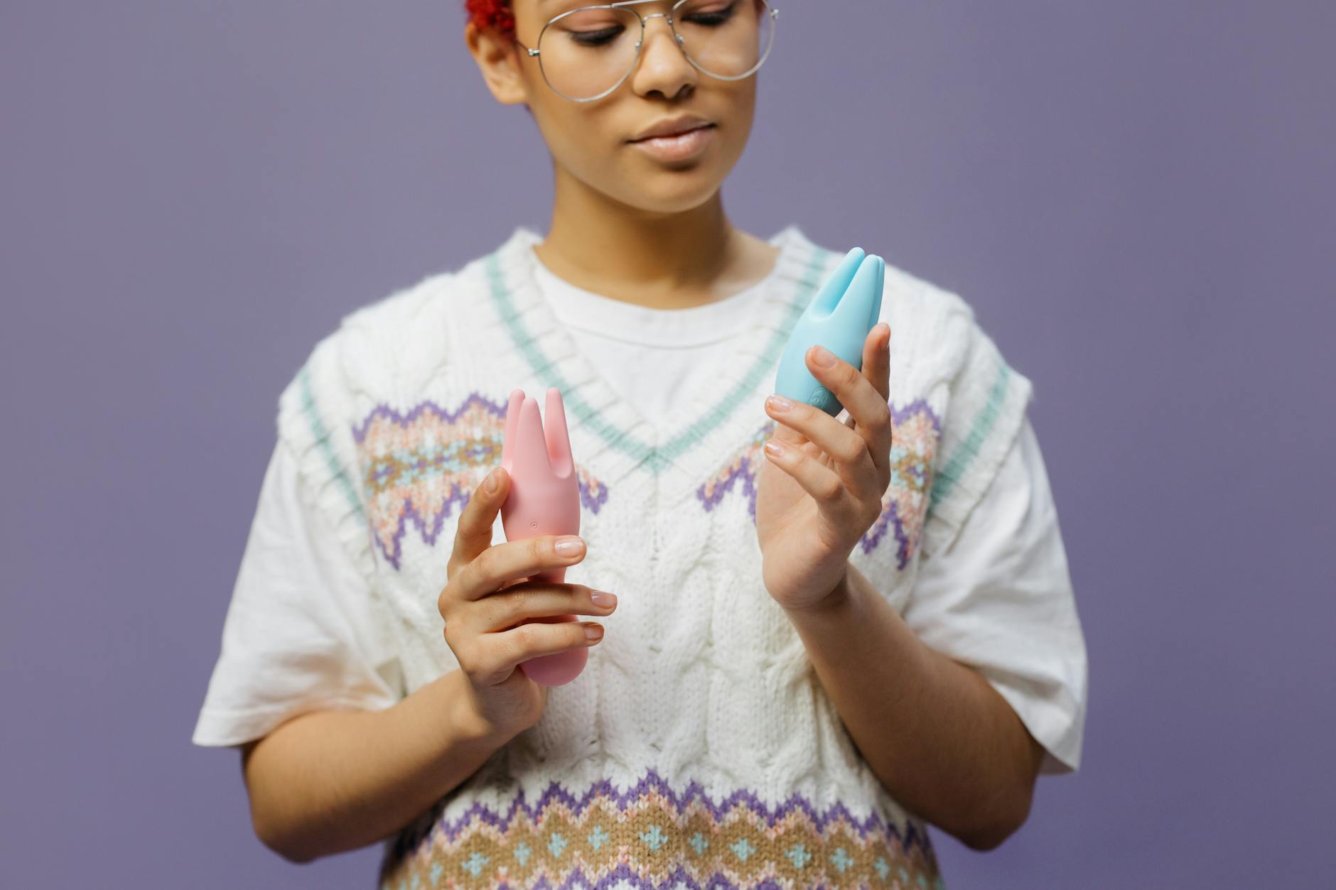 Donna con occhiali che tiene in mano vibratori colorati in silicone blu e rosa