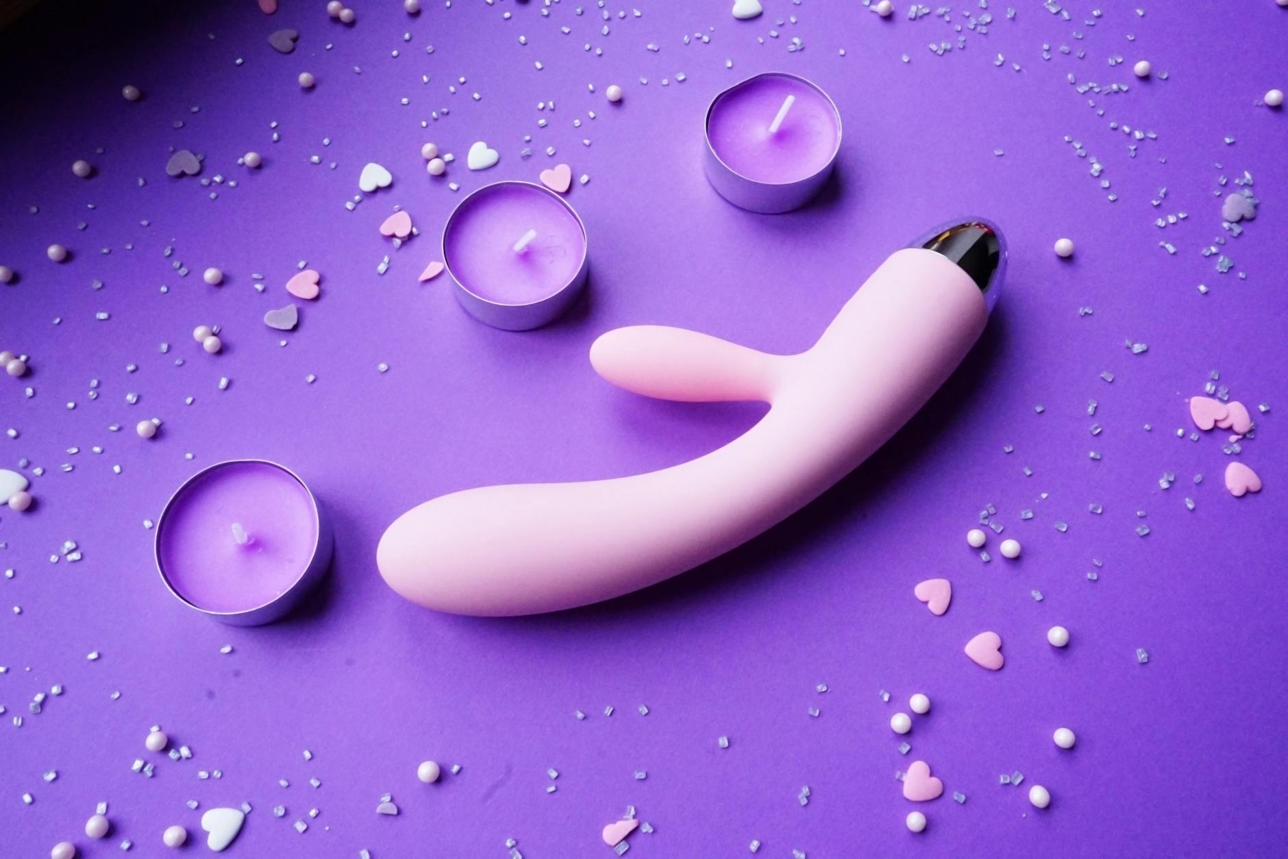 Vibratore in silicone blu tenuto in mano su sfondo viola, un simbolo di consapevolezza del piacere e dell'autocura